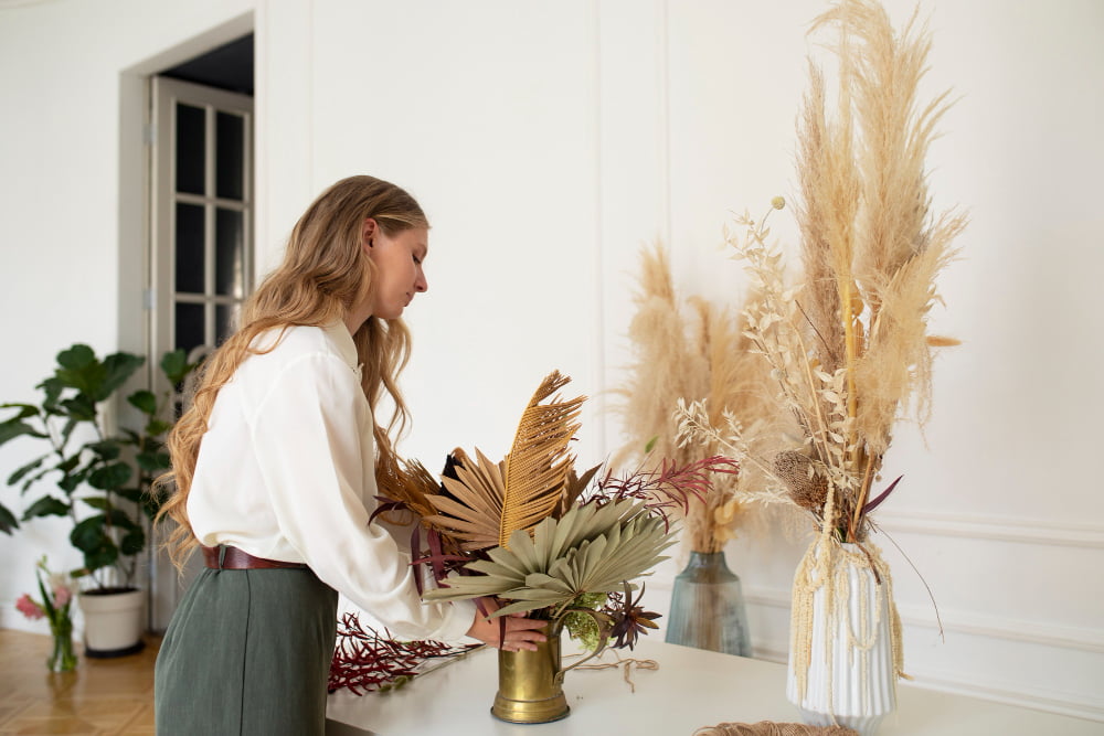 mujer decorando hogar con plantas y flores secas